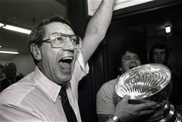 (AP Photo/Pool, File). FILE - In this May 17, 1983, file photo, New York Islanders coach Al Arbour celebrates in the locker room as he holds the Stanley Cup after the Islanders won their fourth cup in a row, beating the Edmonton Oilers 4-2 to sweep the...