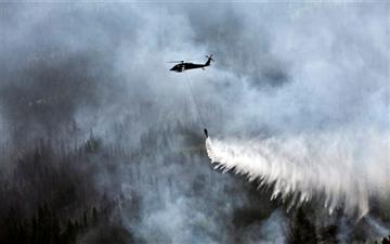 (Sgt. Balinda O’Neal/U.S. Army National Guard via AP, File). FILE - In this June 17, 2015 file photo provided by the Alaska Army National Guard, a “Bambi Bucket,” hanging from a helicopter releases hundreds of gallons of water onto the Stetson Creek Fi...