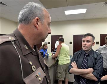 (AP Photo/Timothy D. Easley). David Miller, right, talks with Rowan County Sheriffs Deputy Joe Cline about the possibility of Rowan County Clerk Kim Davis being arrested for contempt at the Rowan County Courthouse in Morehead, Ky., Tuesday, Sept. 1, 20...