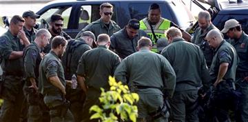(AP Photo/Michael Schmidt). Members of various police agencies gather as they continue searching for suspects in the shooting of a police officer, Tuesday, Sept. 1, 2015 in Fox Lake, Ill. Fox Lake Police Lt. Charles Joseph Gliniewicz was shot and kille...