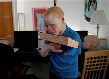(AP Photo/Julie Jacobson). Emmanuel Festo Rutema, 13, carries a dictionary back to a shelf after working on English language exercises with Mwigulu Matonange Magesa, 12, Saturday, Aug. 29, 2015, in Staten Island, N.Y. Emmanuel's surgery attaching a toe...