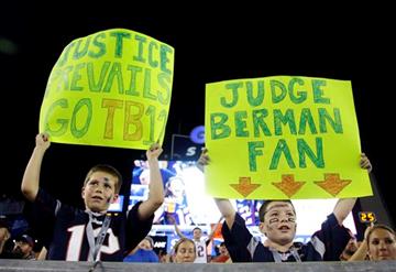 (AP Photo/Stephan Savoia). New England Patriots fans Luke, left, and Andrew Sheridan, of Hanover, Mass., hold signs referring to Federal Judge Richard M. Berman in the first half an NFL preseason football game between the Patriots and the New York Gian...