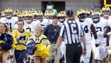 (AP Photo/Rick Bowmer). Michigan head coach Jim Harbaugh leads his team on the field before the start of their NCAA college football game against Utah, Thursday, Sept. 3, 2015, in Salt Lake City.